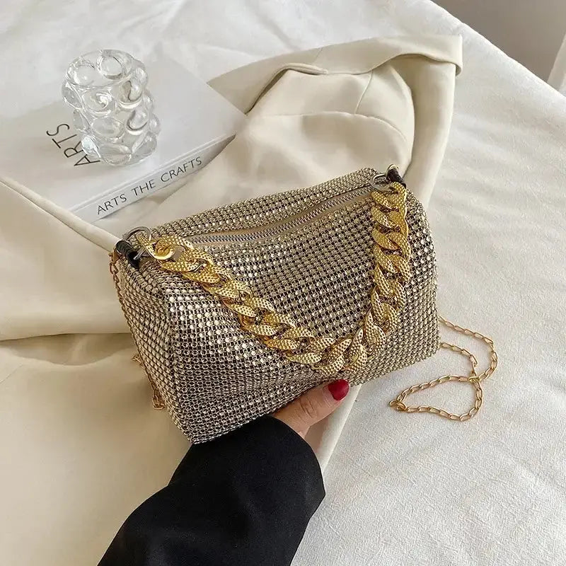 Allover rhinestone bucket bag with gold chain, perfect for prom or casual outings, held in hand on elegant background.