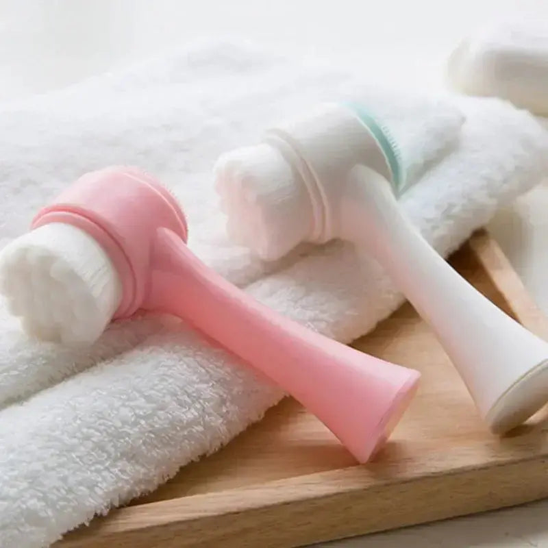 Double-sided silicone facial cleansing brushes in pink and white on a soft towel.