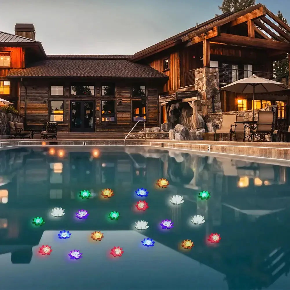 Colorful floating LED lotus lights in a pool near a wooden house, creating a serene ambiance for outdoor relaxation.