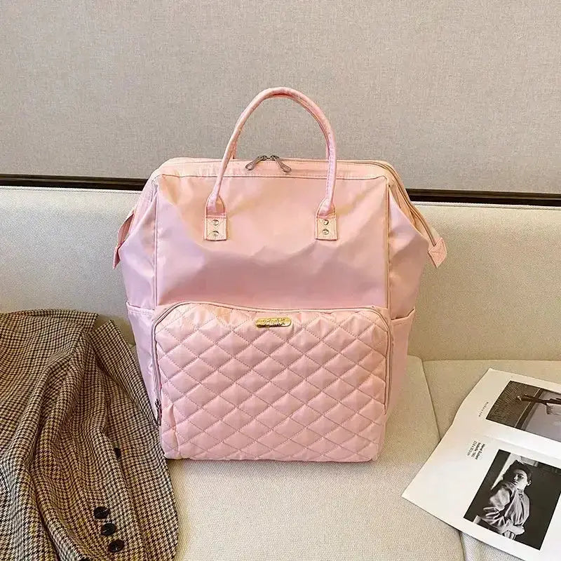 Stylish pink backpack with quilted front pocket, perfect for travel or everyday use.