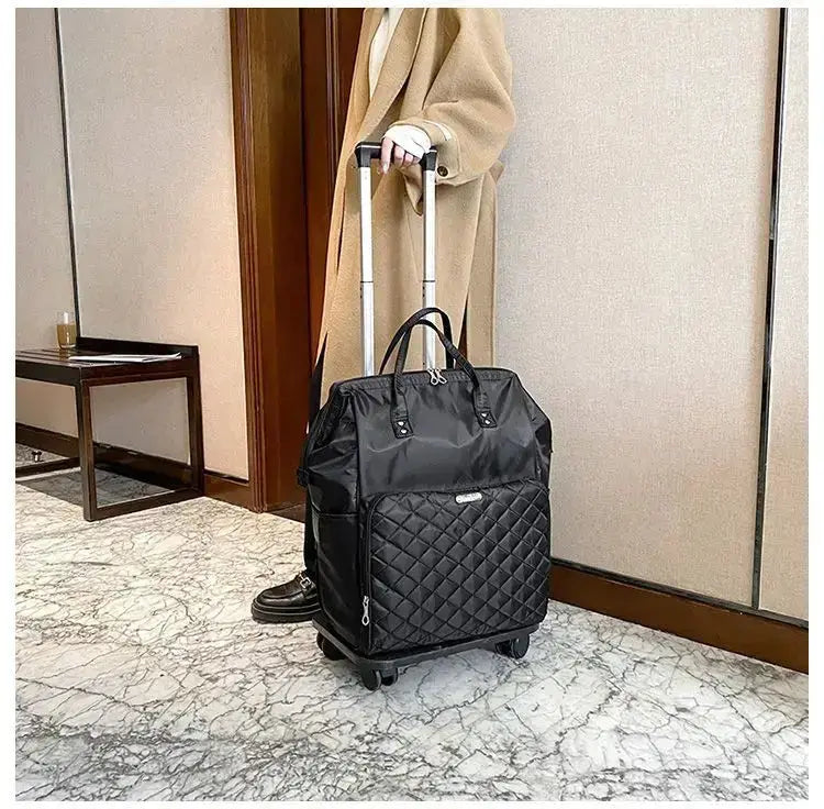 Stylish portable travel bag with wheels, black quilted design, perfect for women, standing in modern interior.