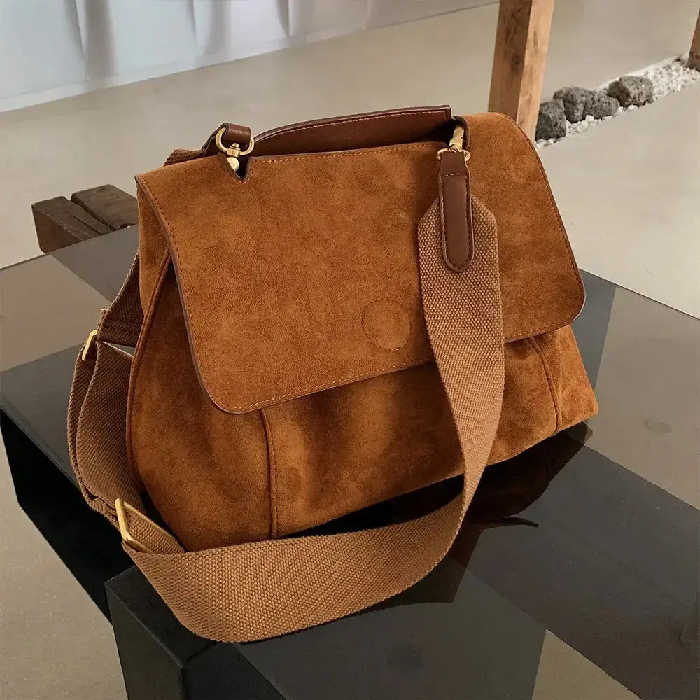Sac à bandoulière en cuir suédé marron avec une bandoulière en tissu, style décontracté et élégant.