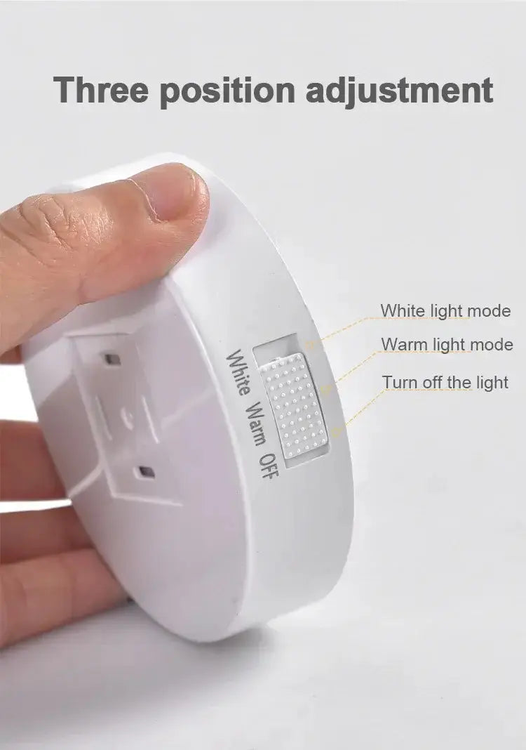 Three position adjustment switch for LED lamp with white and warm light modes, hand-held view.