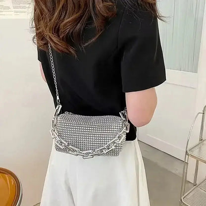 Stylish allover rhinestone mini bucket bag with glitter chain strap, worn by a woman in a modern outfit.