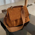 Sac à bandoulière en cuir suédé marron avec une bandoulière en tissu, style décontracté et élégant.